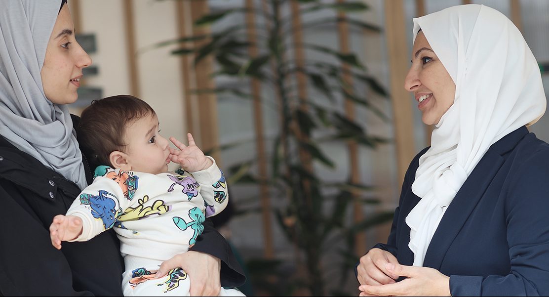 Photo of a staff member speaking to a woman holding a baby